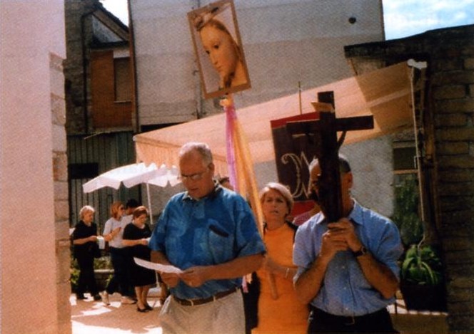 Pellegrini in preghiera con croce e statua della Madonna